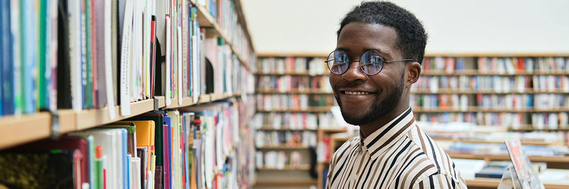 Teen male volunteer smiling and shelving books